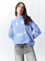 Canguro lila con capucha y cordones ajustables. Estampado frontal con la palabra "Whatever" en letras plateadas.