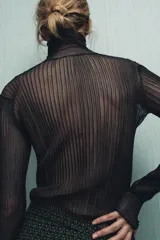 Top semitransparente de punto fino color negro, con cuello subido y manga larga.