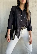Camisa negra con bordado calado, corte recto y aberturas laterales.