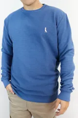 Buzo azul con textura tipo waffle y logo bordado en el pecho.