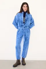 Mameluco de jean con efecto nevado estilo vintage, de corte holgado, mangas largas, cierre frontal con botones a presión y lazo ajustable en la cintura.