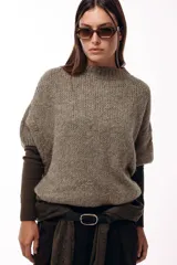 Sweater de tejido de punto grueso con silueta amplia y mangas 3/4. Presenta un diseño relajado con cuello redondo y textura marcada.