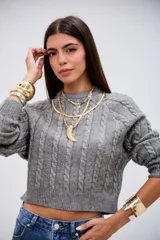 Sweater de punto gris con diseño de trenzas verticales, cuello redondo y corte cropped.