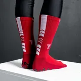 Medias deportivas de caña media color negro, con diseño técnico que incluye zonas de compresión y puntos de silicona antideslizantes en la planta del pie para mayor agarre. Presenta el logo de la marca en el lateral.