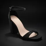 Sandalias de fiesta color negro con acabado brillante, diseño de tira delantera y pulsera al tobillo con cierre de hebilla. Presentan un taco cuadrado alto y robusto, también cubierto de material brillante.