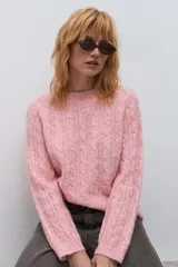Sweater de punto con diseño de trenzas verticales, color rosa melange, de cuello redondo y manga larga con puños acanalados.