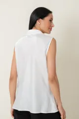 Blusa blanca sin mangas con cuello drapeado que termina en lazo.