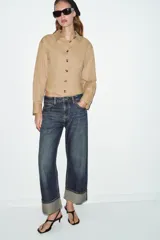 Jeans de tiro medio con corte relax fit y pernera holgada. Presenta diseño de cinco bolsillos, cierre frontal con cremallera y botón, y bajo con vuelta marcada.