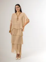 Vestido largo color beige de seda italiana, con falda de volados y sobrecapa superior. Confeccionado en tejido liviano y fluido con diseño elastizado.