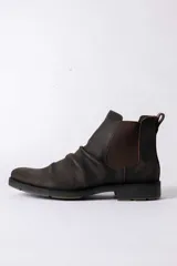 Bota tipo Chelsea de cuero color marrón oscuro con efecto desgastado, paneles laterales elásticos y suela de goma antideslizante.