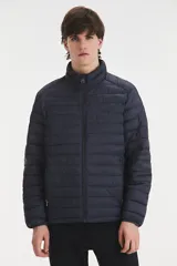 Campera puffer de color azul oscuro, con diseño acolchado horizontal, cierre frontal completo y cuello alto. Cuenta con bolsillos laterales con cierre y mangas largas.