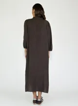 Vestido largo color beige de lino, con cuello mao, mangas 3/4 abullonadas y cierre frontal con botones. Presenta volantes verticales en el frente.