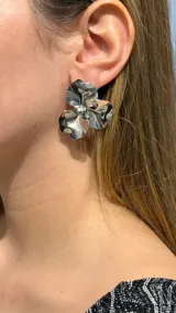 Caravanas de diseño floral con acabado metálico plateado brillante, con pétalos de forma orgánica y centro abultado.