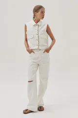 Pantalón de jean blanco, de calce recto y tiro medio-alto. Cuenta con un corte en la rodilla y ruedo desflecado.