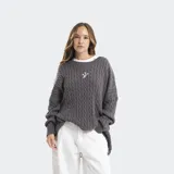 Buzo tejido de punto ochos, color gris oscuro, con cuello redondo, mangas largas y detalles de efecto desgastado en puños y ruedo. Presenta un pequeño logo bordado en el centro del pecho.