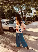 Sweater color crema con bordados geométricos en azul, verde, rojo y marrón. Tiene cuello redondo y mangas largas. Corte holgado.