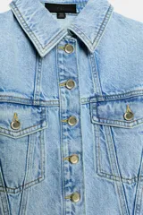 Cazadora corta de denim color celeste con cuello solapa, manga larga y hombreras. Cuenta con bolsillos delanteros con solapa y cierre frontal de botones metálicos.
