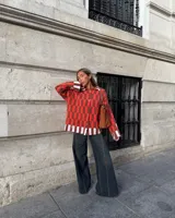 Saco de punto con diseño de cuadros en tonos rojo y marrón, con detalles en color crema en los bordes. Presenta cuello camisero, cierre frontal con botones en forma de corazón y dos bolsillos delanteros.