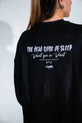 Buzo de tejido de punto fino en color negro, con diseño de cuello redondo y corte holgado. Presenta un estampado gráfico estilo gótico en el centro del pecho.
