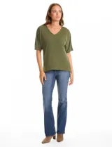 Blusa de silueta fluida con escote en V, manga japonesa corta y costura central vertical en el frente. Confeccionada en tejido de punto con acabado mate, presenta un diseño con largo asimétrico, siendo más larga en la espalda.
