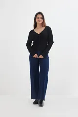 Sweater negro de tejido de punto acanalado, con escote en V y cierre frontal con cremallera circular.