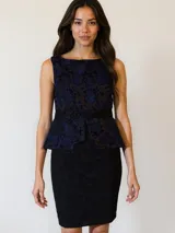 Vestido de fiesta negro con encaje floral azul, sin mangas, corte a la rodilla y falda tubo.