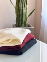 Sweater de punto acanalado color bordó, con cuello redondo, mangas largas con puños ajustados y diseño holgado con tajos laterales en el ruedo.