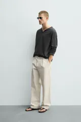 Camiseta de manga larga con corte relajado, confeccionada en algodón. Presenta un cuello redondo amplio con acabado irregular y detalle de botones frontales a tono.