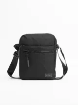 Morral de diseño compacto y funcional, confeccionado en tela resistente color negro. Cuenta con múltiples compartimentos con cierre, incluyendo bolsillos frontales y traseros para una organización óptima. Incluye una correa ajustable para llevar al hombro o cruzado, con detalle de etiqueta de marca en la parte inferior.