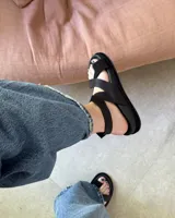 Sandalias negras de cuero vacuno con tiras cruzadas y hebilla lateral.