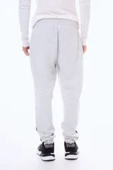 Pantalon de jogging de felpa en color gris melange, con cintura elástica ajustable mediante cordones, puños en los tobillos y paneles laterales en contraste de color negro en la parte inferior de las piernas.
