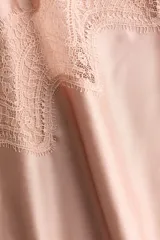 Top largo de satén rosado con breteles finos ajustables, escote en V y diseño asimétrico decorado con ribetes de encaje floral.