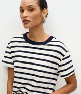 Remera de corte boxy confeccionada en algodón, con diseño de rayas horizontales en blanco y negro, cuello redondo en color negro contrastante y mangas cortas.
