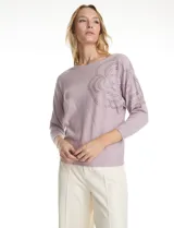 Buzo de tejido de punto fino marca LIV Milano, color violeta, con diseño de manga japonesa y largo tres cuartos. Presenta un aplique de brillos en la parte frontal y lateral que forma un diseño floral.