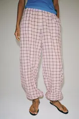 Pantalón bombacho de tiro medio, confeccionado en mezcla de algodón con estampado de cuadros en tonos rosados y oscuros. Presenta cintura elástica y bajo abullonado con puño elástico.