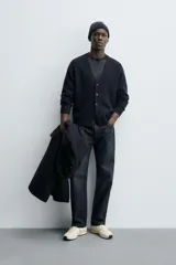 Cárdigan de punto en color verde oscuro, con cuello en pico, manga larga y cierre frontal con botones. Presenta acabados en rib en puños y bajo.