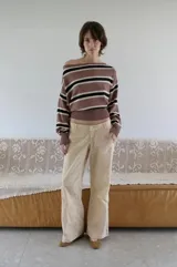 Buzo tejido de punto con escote bote, diseño a rayas horizontales en tonos marrón, negro y blanco. Presenta mangas largas con puños ajustados y una faja ancha en la cintura.