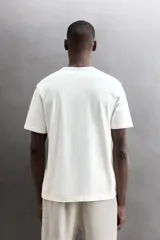 Camiseta de algodón gris melange con cuello redondo, mangas cortas y efecto lavado. Presenta un estampado de texto frontal en color oscuro con efecto desgastado.