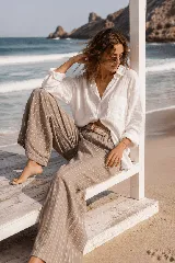 Pantalón de lino azul marino con finas rayas verticales blancas, de corte amplio y talle alto. Incluye bolsillos funcionales y una cintura elástica con cinturón de rafia desmontable.