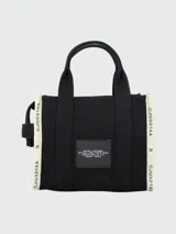 Cartera tipo tote bag de lona negra con letras blancas estampadas en el frente. Cuenta con doble asa superior, correa ajustable y desmontable, y detalles laterales en contraste.