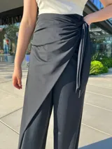 Pantalón negro de vestir con corte palazzo, cintura alta con lazo y abertura lateral.