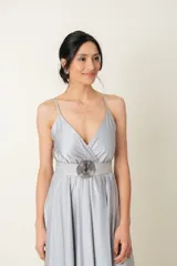 Vestido largo de satén color gris plateado, con breteles finos, escote cruzado y corte debajo del busto.