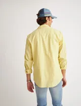 Camisa amarilla de manga larga confeccionada en tela tipo lino, con bolsillo en el pecho, botones de pasta y calce clásico.