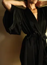 Kimono de seda negra con lazo ajustable en la cintura, mangas amplias y cuello solapa.