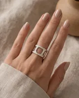 Anillo ancho de acero plateado con textura martillada y diseño geométrico abierto con un cuadrado central.