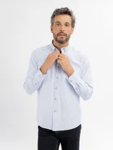 Camisa de manga larga con diseño de rayas finas, cuello con botones y bolsillo frontal. Presenta cierre de botonadura frontal y corte regular.