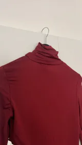 Top de cuello alto color bordó, con manga larga y abertura en el abdomen.
