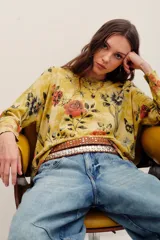 Sweater de punto color mostaza con estampado floral y de mariposas, cuello redondo y mangas largas.