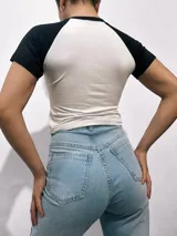 Remera corta blanca con mangas raglán de diferentes colores y estampado frontal con la leyenda "Malibu California A Beautiful Place".