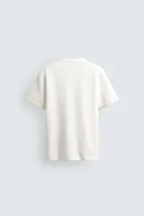 Camiseta de manga corta con cuello panadero y cierre frontal de tres botones. Presenta una textura acanalada y un corte regular fit.